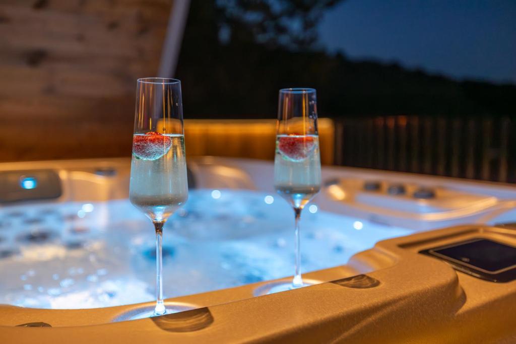 two wine glasses sitting on a table with a hot tub at HillsideHome Donnerskirchen, Neu ab 10-2025 in Donnerskirchen
