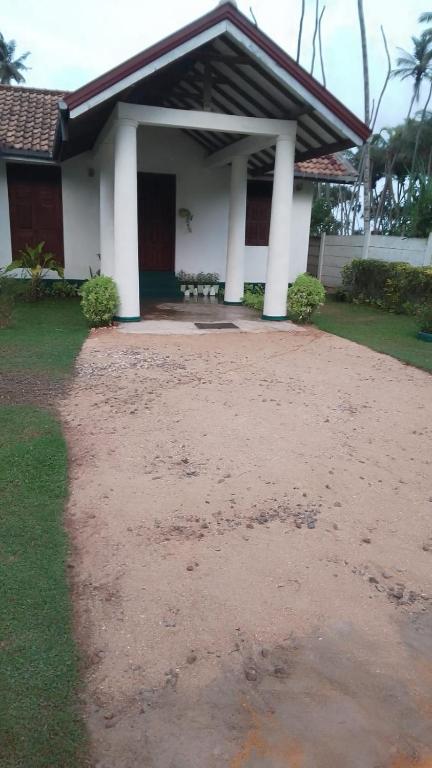 a house with a dirt driveway in front of it at Coco Villa Payagala in Paiyagala South