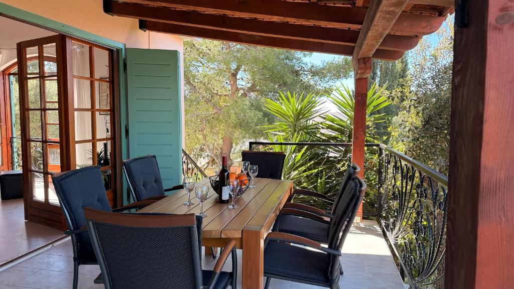 a wooden table and chairs on a porch with a glass door at Villa Punta in Maslinica
