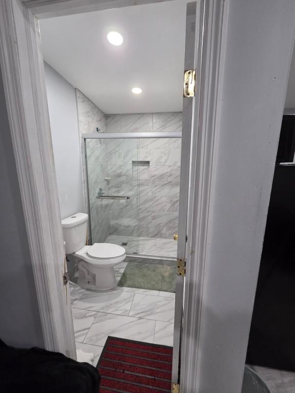 a bathroom with a toilet and a glass shower at Newly built Studio in Irvington