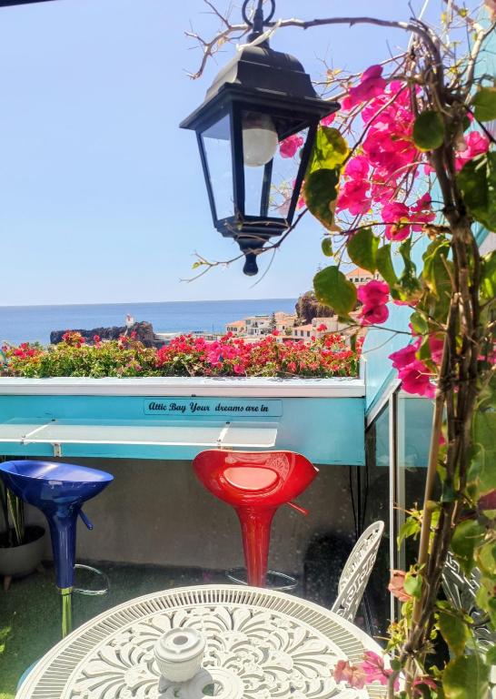 a table and chairs and a lamp and flowers at ATTIC BAY - Cozy Stay with Sea View in Câmara de Lobos