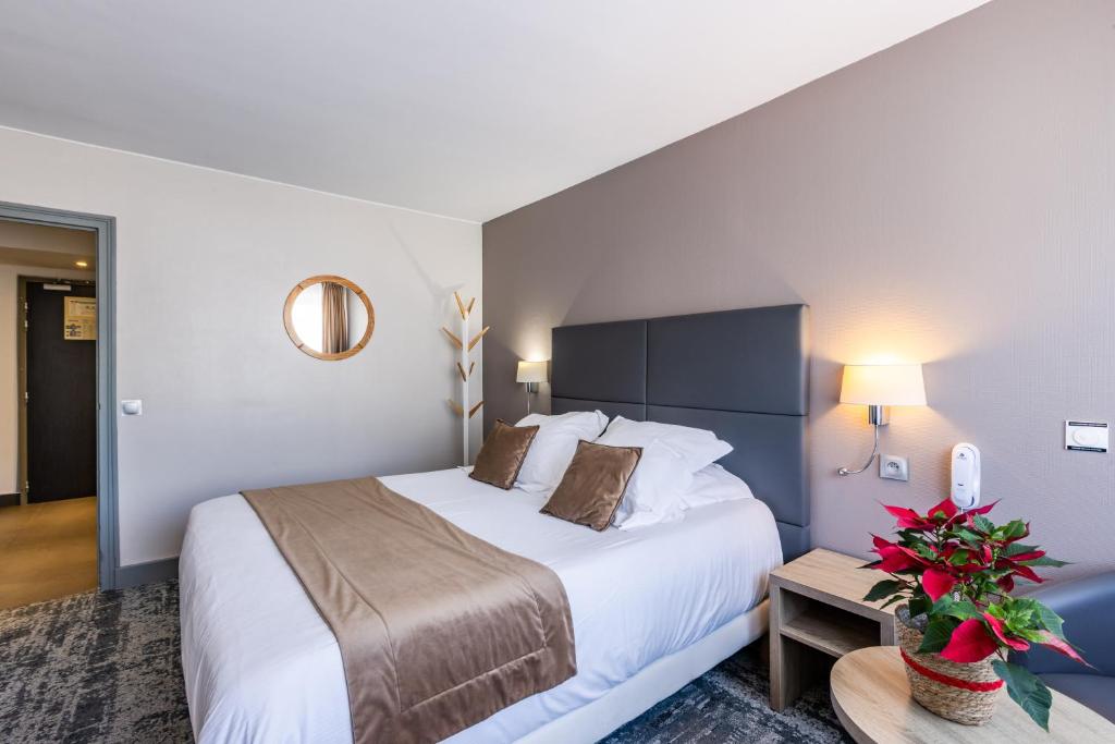a hotel room with a large bed and a table at Hotel Vauban Briançon Serre Chevalier in Briançon