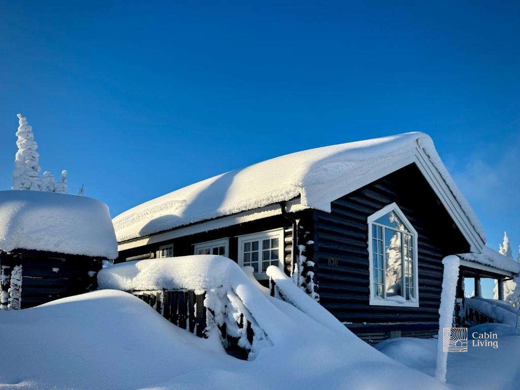 a log cabin covered in snow with a roof at Authentic mountain atmosphere at Sjusjøen in Ringsaker