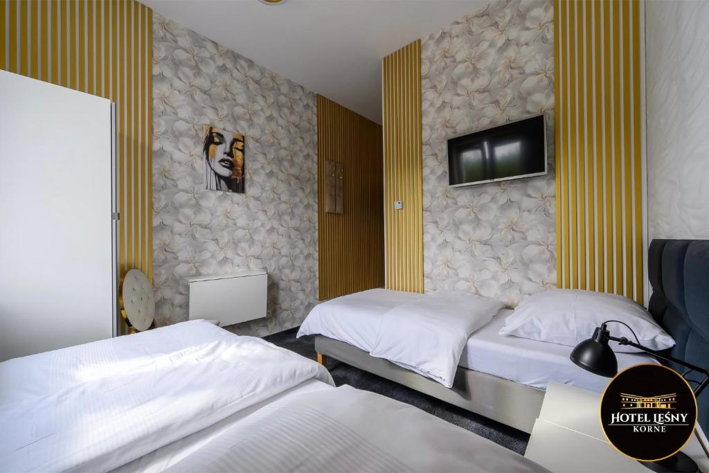 a bedroom with two beds and a tv on the wall at Hotel Leśny Korne koło Kościerzyny - Kaszuby in Korne