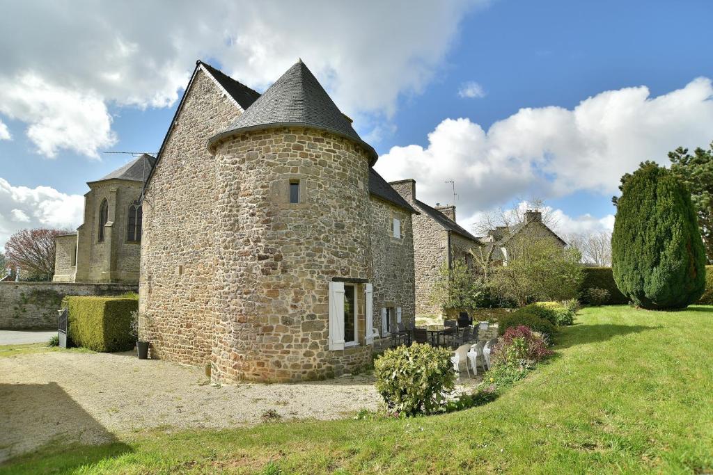 an old stone house with a turret on a grass field at La tourelle du Val-d'Arguenon in Pluduno