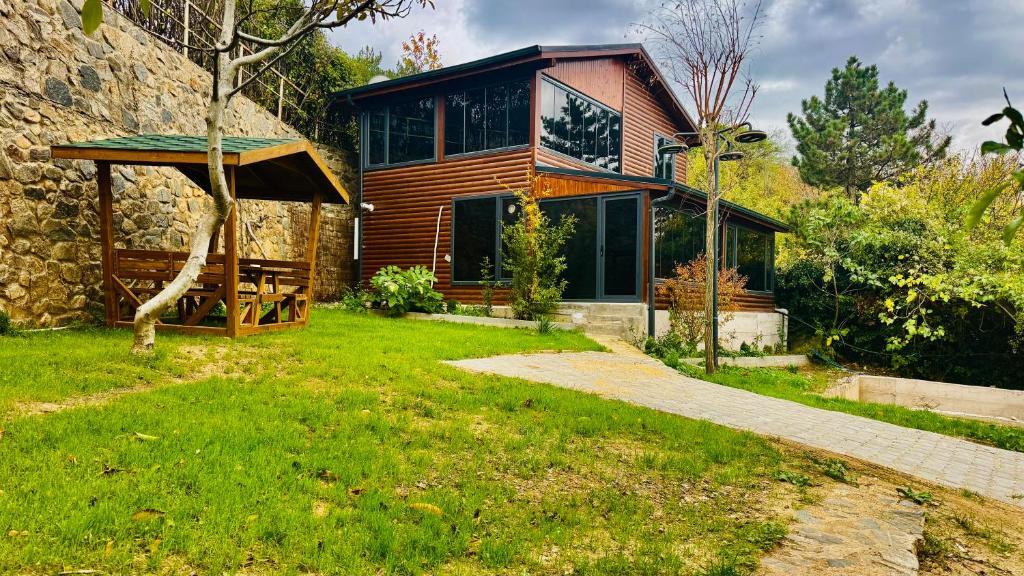 a wooden house with a green lawn in front of it at Uludağ Vadi Konakları in Bursa
