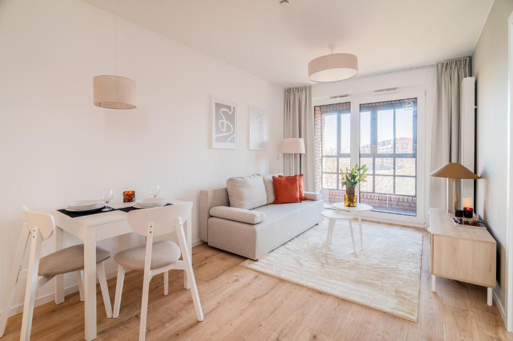 a white living room with a table and a couch at Prime Apartments Gdańsk in Gdańsk