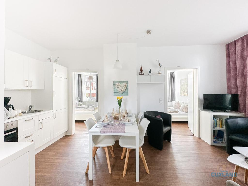 a kitchen and dining room with a white table and chairs at Hus Krüüzpadd unnen in Cuxhaven