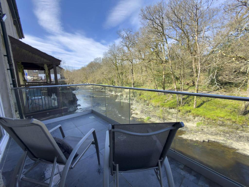 a balcony with two chairs and a table and a window at Beautiful River View with Sauna in Llandysul