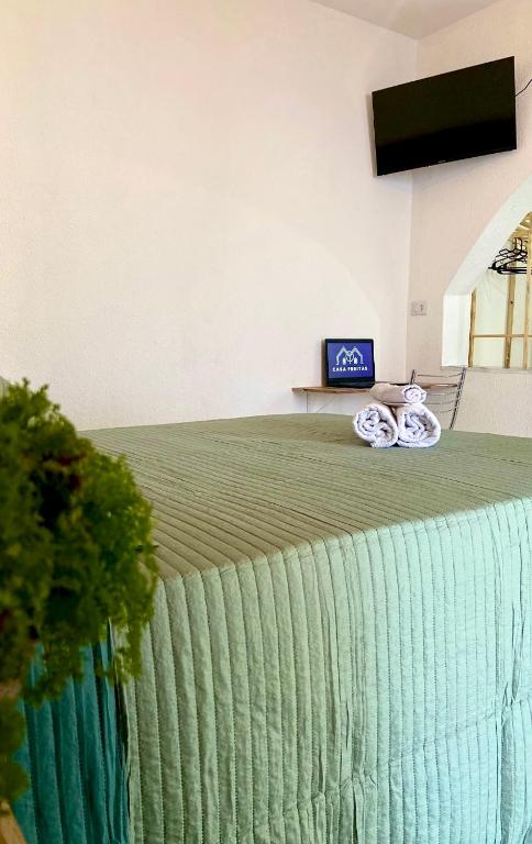 a bed with green sheets and a tv on top at Casa Freitas - suíte 1 in Extrema