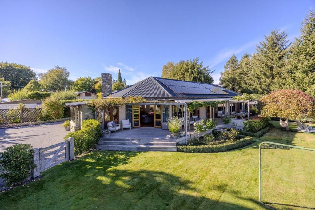 a house with a porch and a lawn at Wanaka Lakeside Serenity at Eely Point with Pool in Wanaka