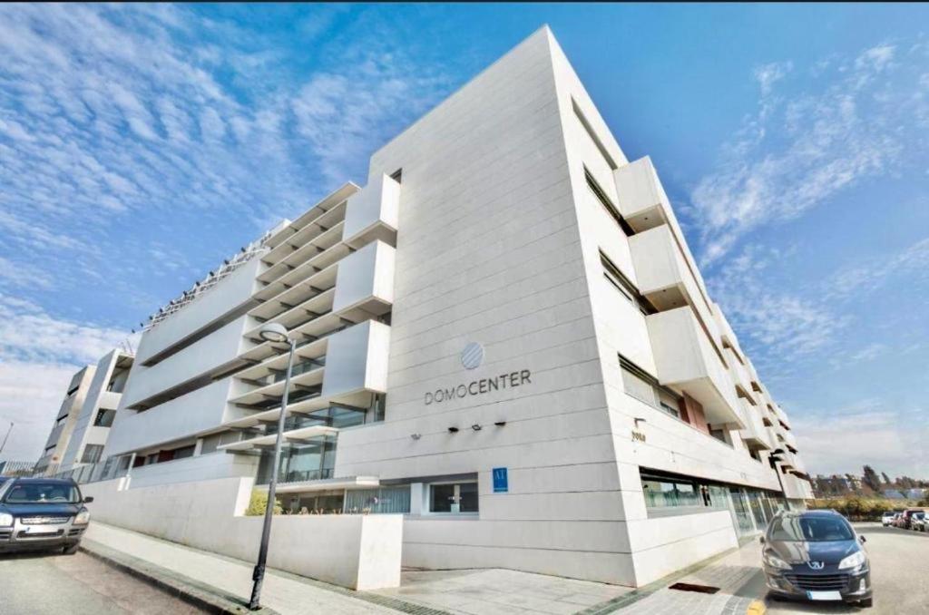 a white building with cars parked in front of it at Domocenter Apartamentos Turísticos in Bormujos