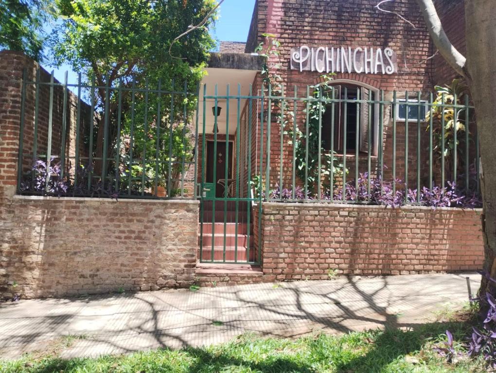 an iron gate on a brick building with purple flowers at Casa Garú in Paso de los Libres