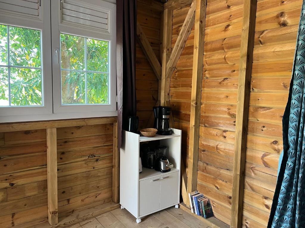 a room with wooden walls and a white shelf with a coffee maker at Ti Bwa in Sainte-Luce
