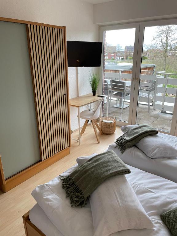 two beds in a room with a balcony with a table at Fewo Auenblick in Ascheberg