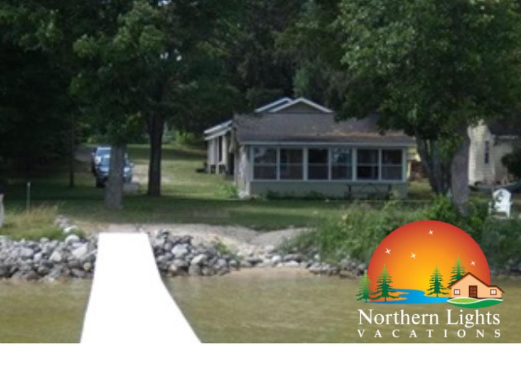 a house with a sign that says northern lights accidents at Sandy Bottom Cottage on Intermediate Lake in Bellaire