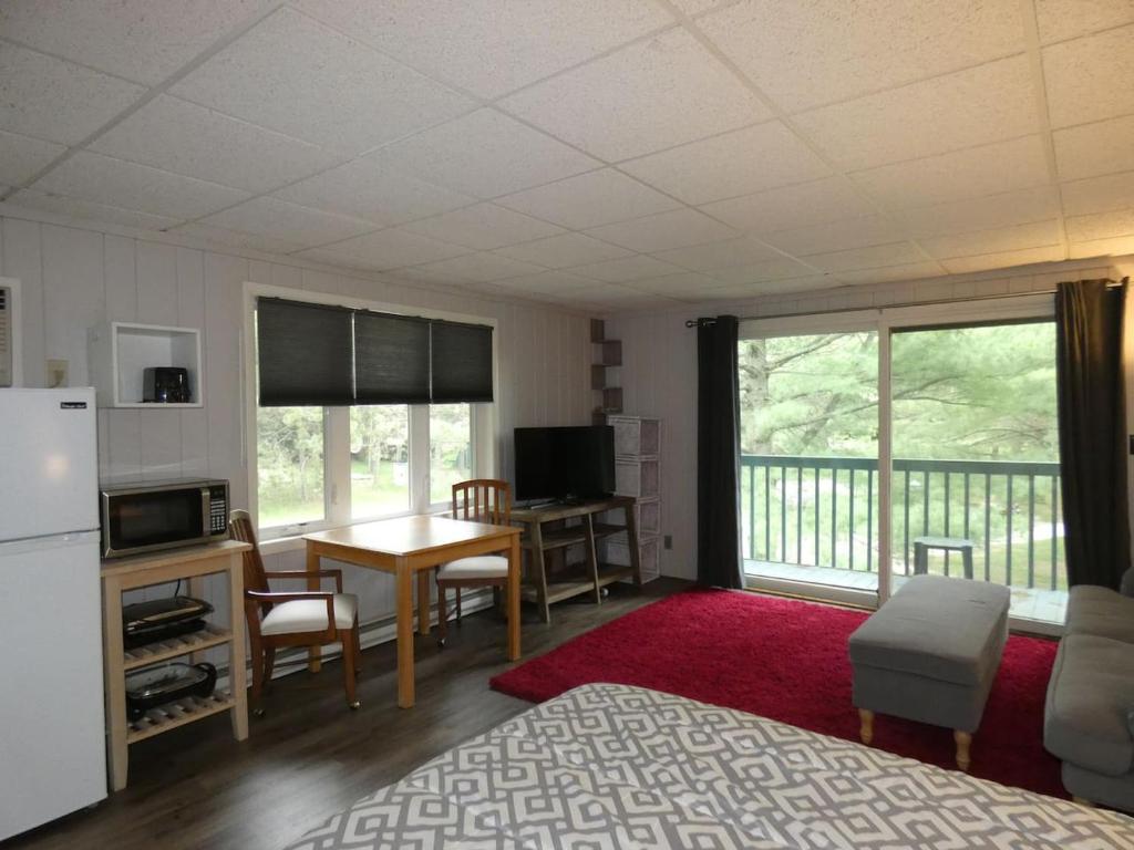 a room with a kitchen and a living room with a refrigerator at Happy Hour at Windcliff! Studio condo at Shanty Creek Resort in Bellaire