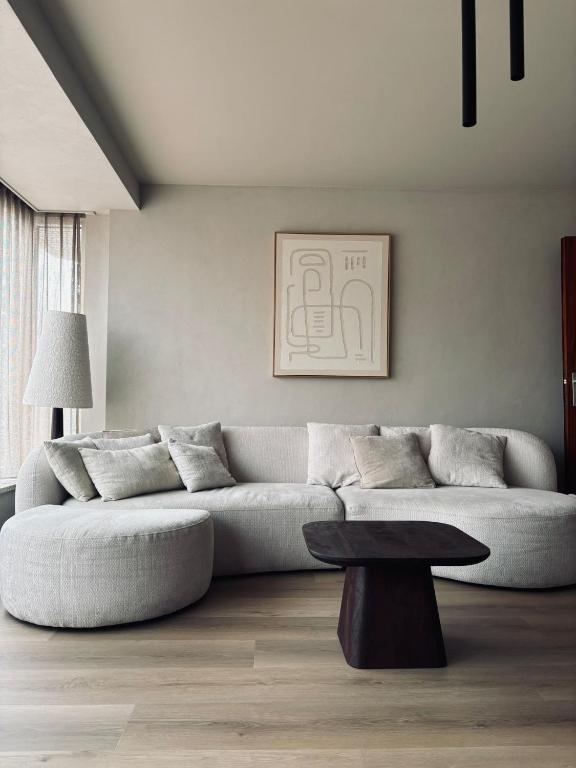 a living room with a couch and a table at Ruim, stijlvol gerenoveerd vakantieappartement voor 4 personen vlak bij zee en de duinen in De Panne