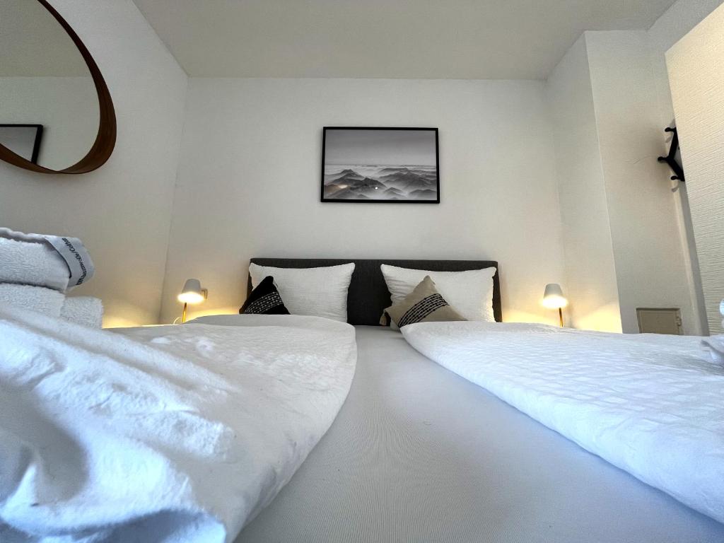 two beds in a room with white sheets and pillows at Seeuferresidenz am Adrian Stoop NEU eingerichtet in Bad Wiessee