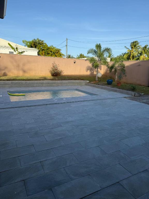 a patio in a yard with a wall at La jolie Villa in Le Lamentin