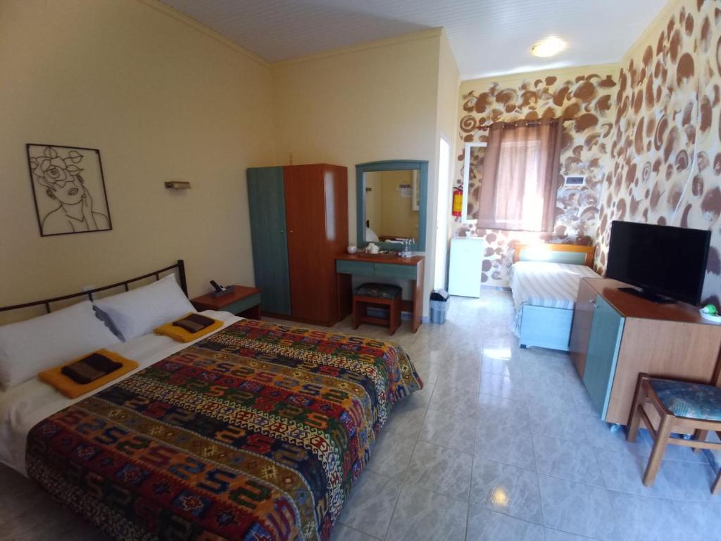 a bedroom with a bed and a television and a couch at Panorama Rooms in Kyllini