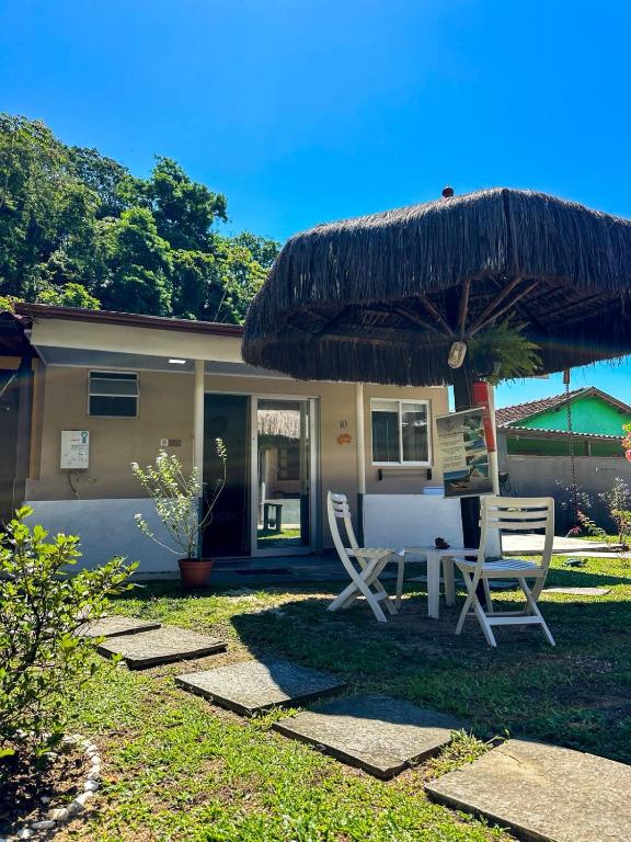 a house with two chairs and a table and an umbrella at Bella Mar Suítes in Angra dos Reis