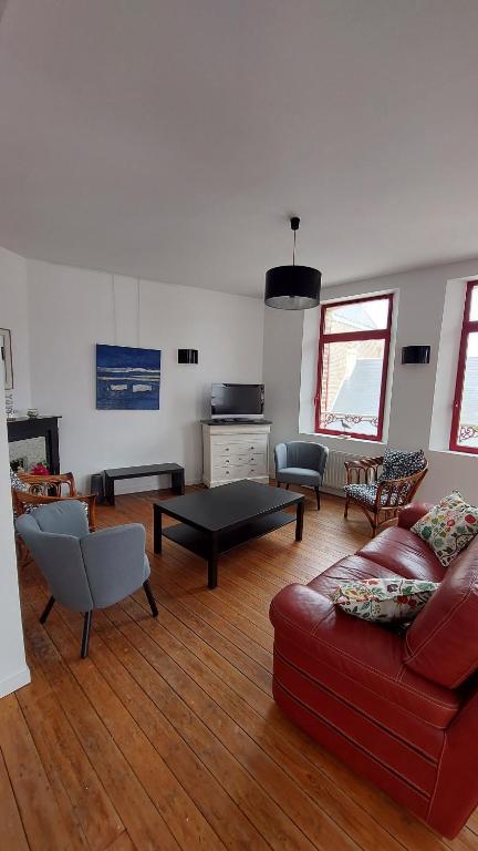a living room with a red couch and a table at Les 3 conserveries in Le Crotoy