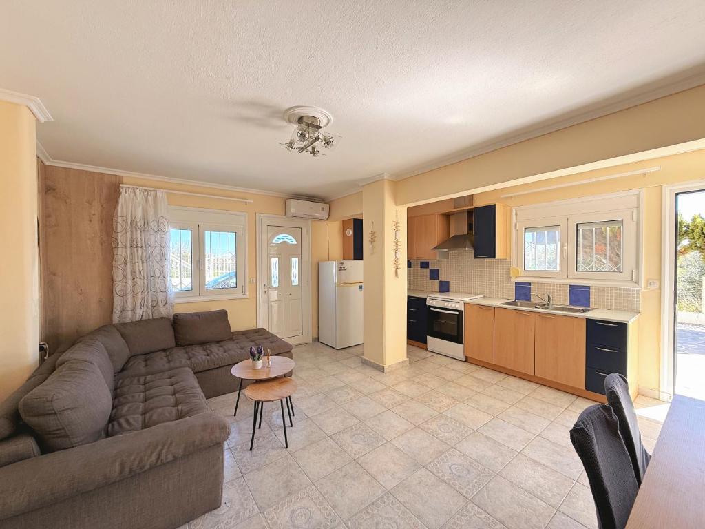 a living room with a couch and a kitchen at Elena's 3BR Maisonette with Garden & Pool in Nea Plagia