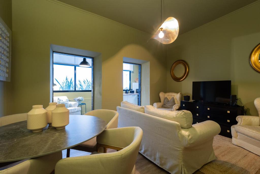 a living room with a table and white chairs at Espaço Calheta in Ponta Delgada