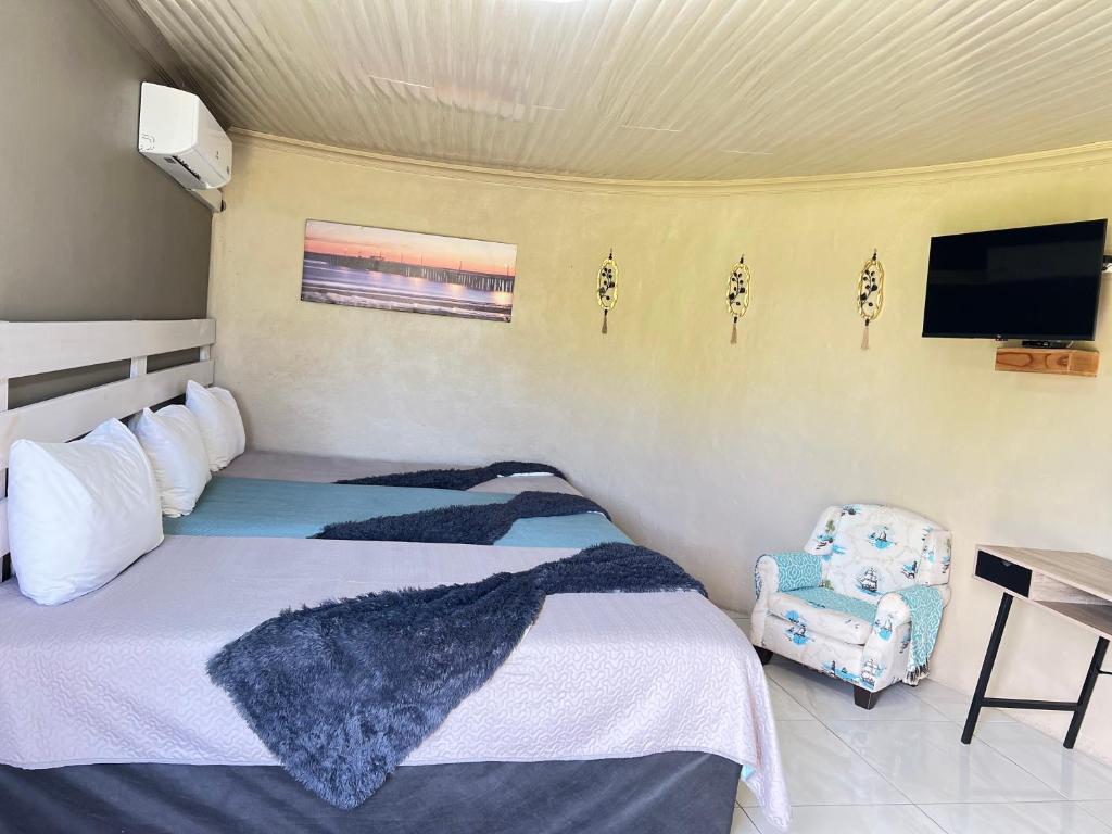 a bedroom with a bed and a chair and a television at Mbizana Lifestyle in Monzi