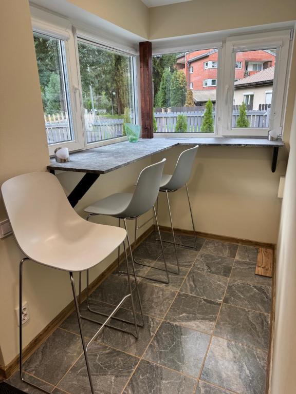 a kitchen with white chairs and a counter with windows at Lielupes Apartments Jurmala in Jūrmala