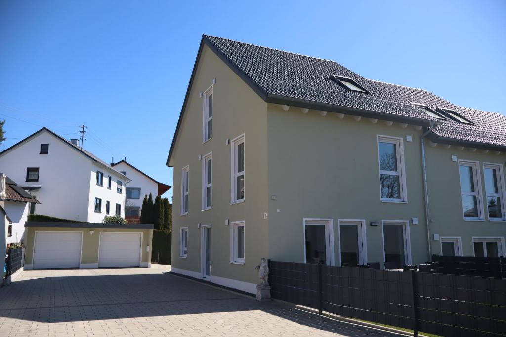 a white and gray house with a black fence at Ferienhaus Ferati - Modernes Neubau-Haus & nahe Legoland in Günzburg