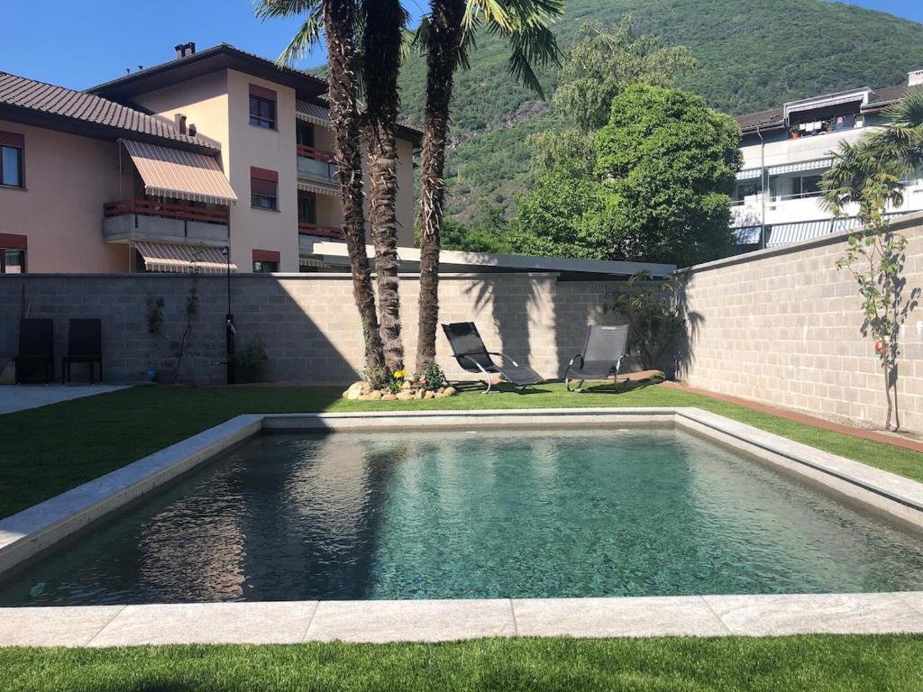 a swimming pool in a yard next to a building at Elegant apartment with pool and parking in Losone