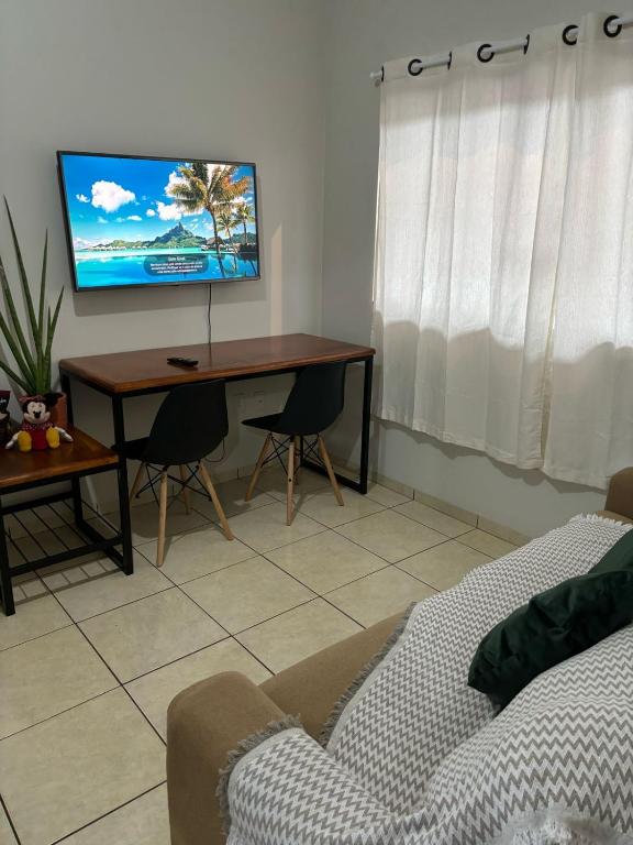 a living room with a desk with a tv on the wall at Ap Perfeito! Condomínio fechado e garagem coberta in Tangara da Serra