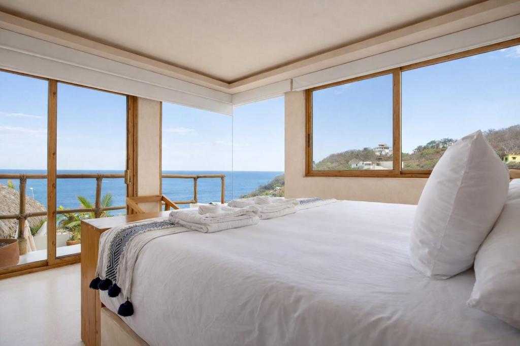 ein Schlafzimmer mit einem Bett und Meerblick in der Unterkunft Xeno Hotel Boutique in Playa Estacahuite