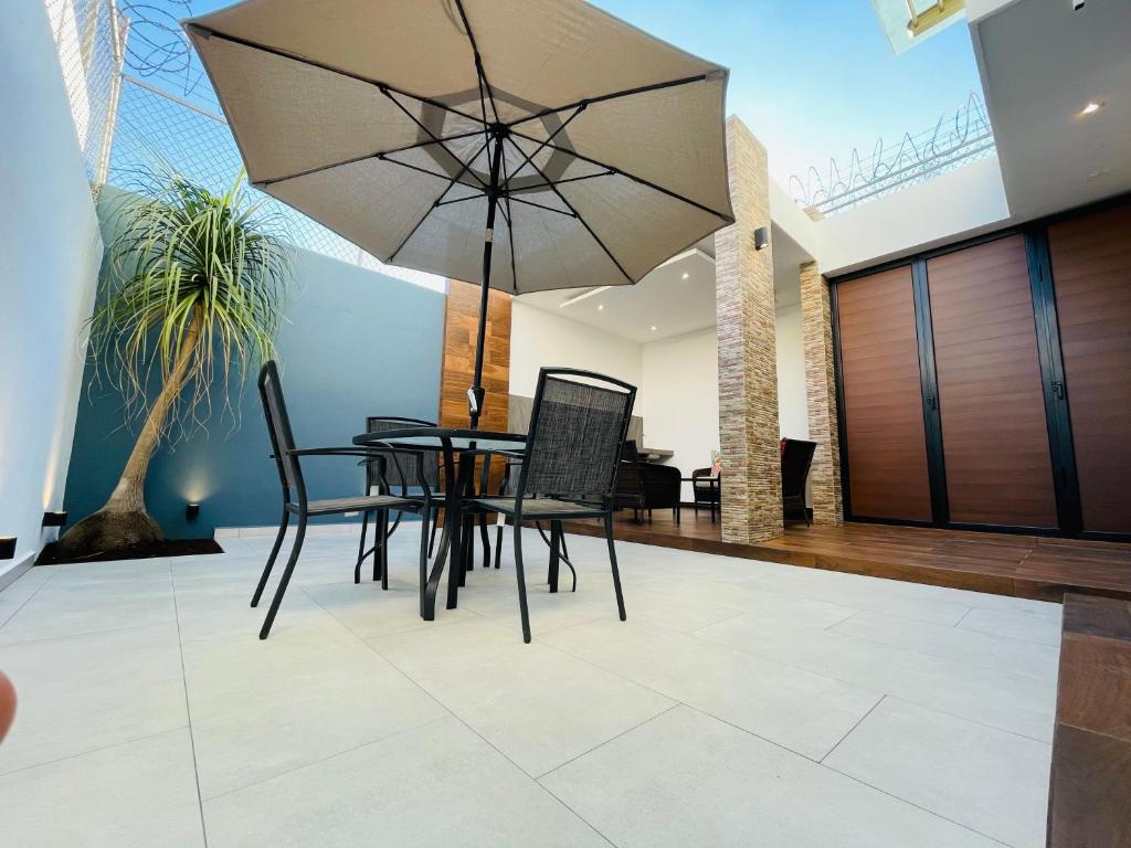 a dining room with a table and chairs and an umbrella at Casa Fénix in Tepic