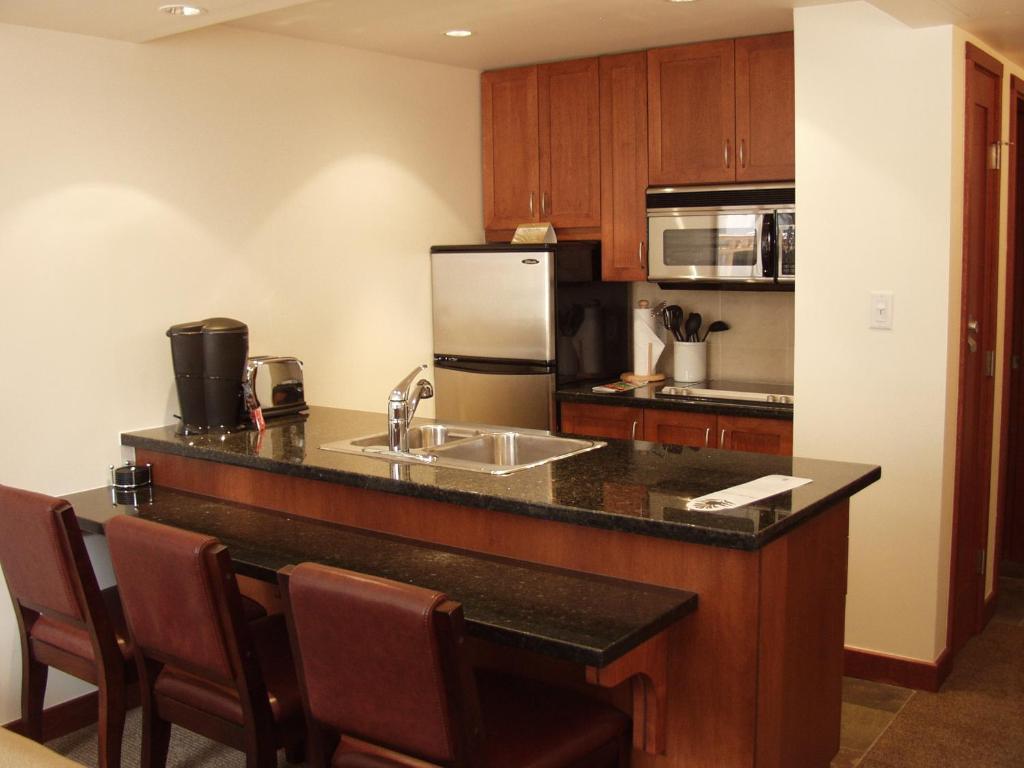 a kitchen with a counter with a sink and a refrigerator at Pan Pacific Whistler Village Centre in Whistler