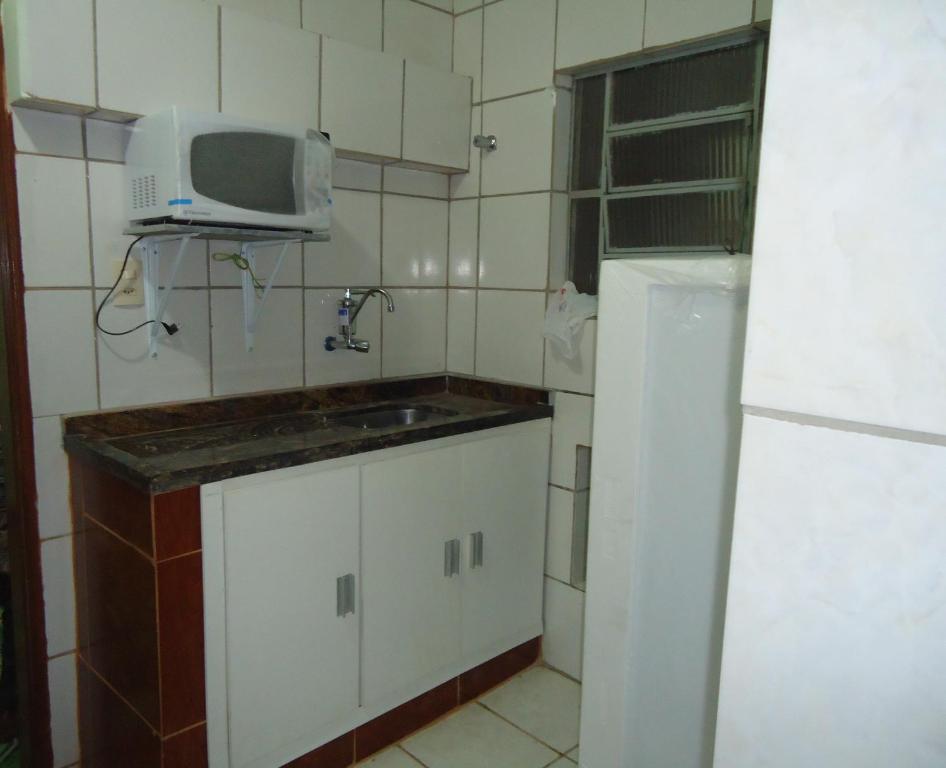 a small kitchen with a sink and a microwave at Pousada Popular in Três Marias