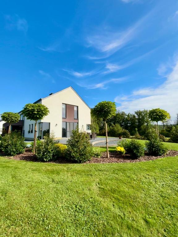 a white house with trees in a yard at Le Daguet pour 8 in Florenville
