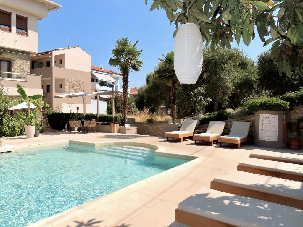 a swimming pool with chairs and a building at Aroma Villa & Studios in Limenas