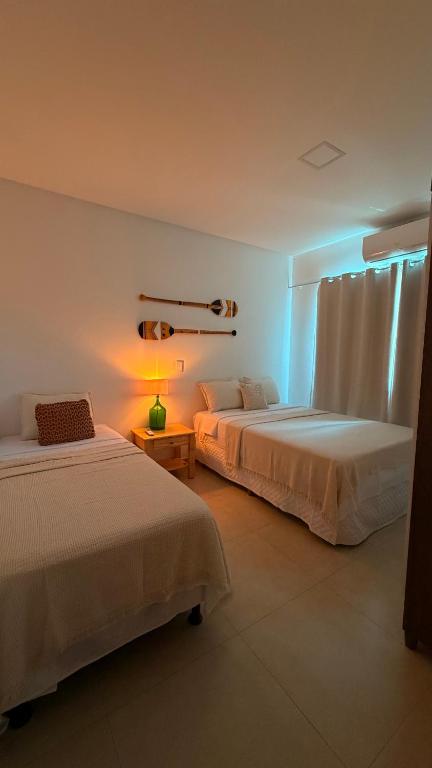 a bedroom with two beds and a lamp on a table at Espaço Move in Porto Seguro