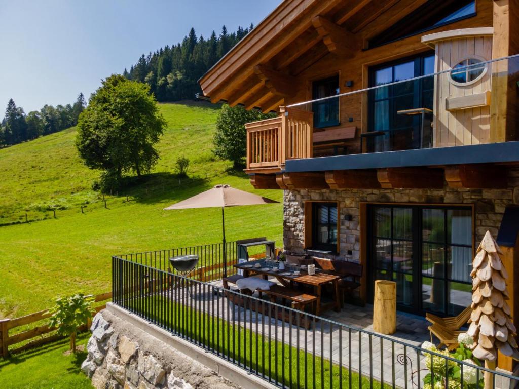 a house with a balcony with a table and an umbrella at Tauernlodge Wagrain Edelweiss 42E in Wagrain