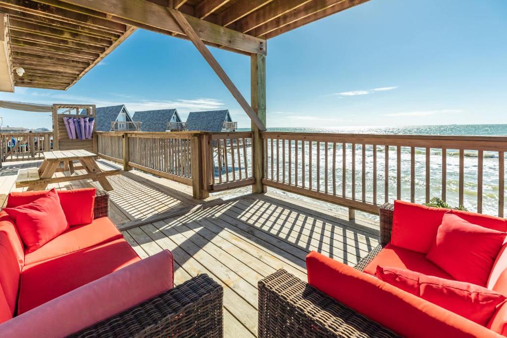 a deck with two couches and a view of the ocean at Paradise Point - Barefoot Beachfront Living in Surfside Beach