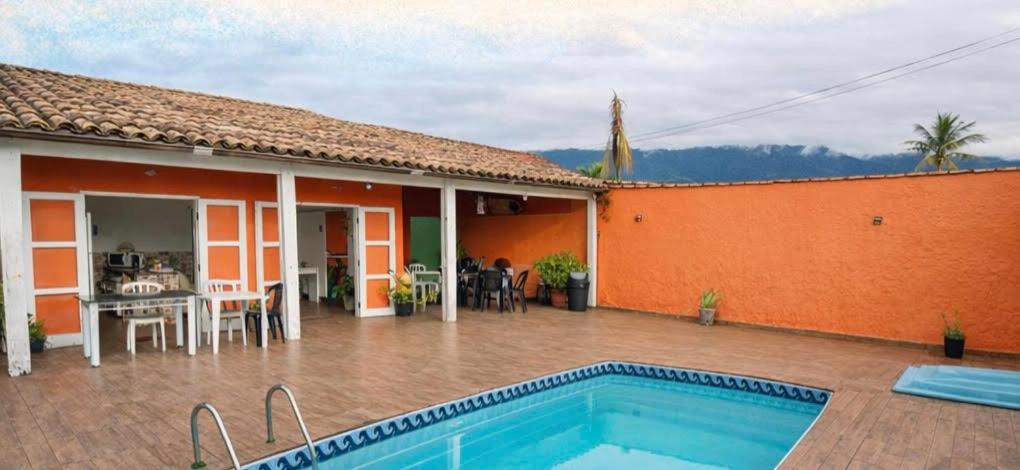 a villa with a swimming pool in front of a house at Pousada da Sú in Bertioga