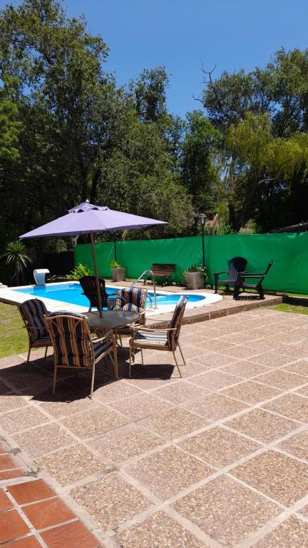a patio with a table and chairs and an umbrella at Cabaña LA SOÑADA in Villa Anizacate