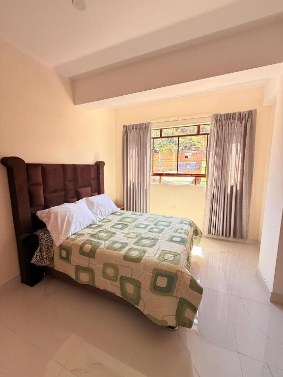 a bedroom with a bed with a green bedspread and a window at Refugio del Viajero in Carhuaz