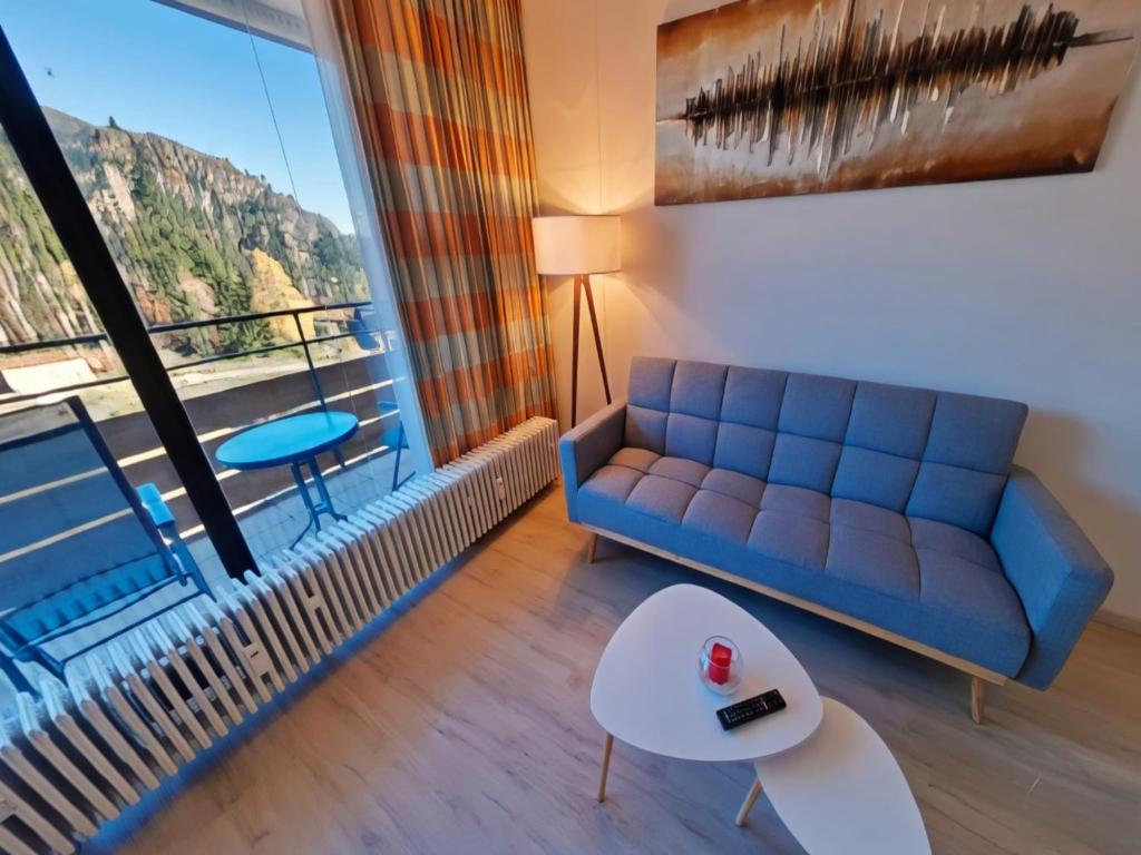 a living room with a blue couch and a large window at Studio Roswitha mit Pool und Sauna in Freyung