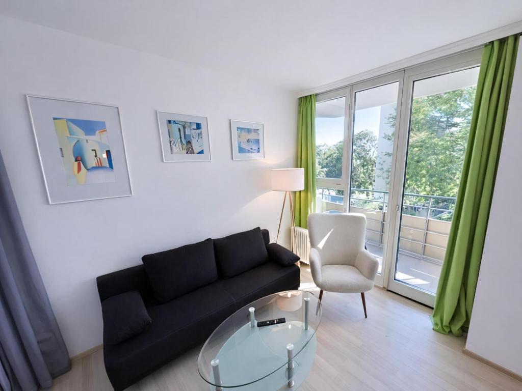 a living room with a black couch and a glass table at Studio Michaela mit Pool und Sauna in Freyung