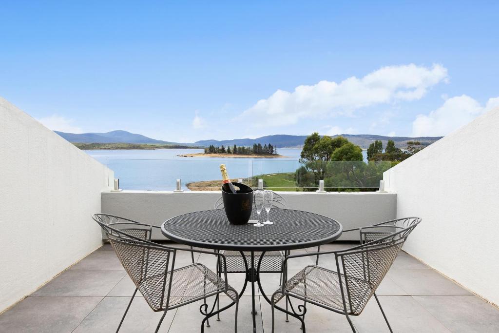 a table on a balcony with a view of the water at Horizons Lake Jindabyne in Jindabyne