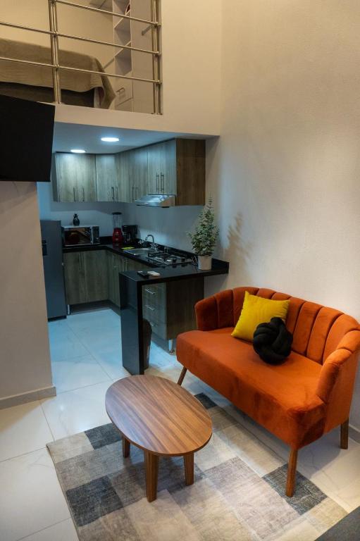 a living room with an orange couch and a table at Urban Loft Hotel Federalismo in Guadalajara